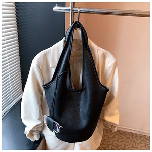 Close-up of black lychee grain bucket bag on white blazer background showing leather texture