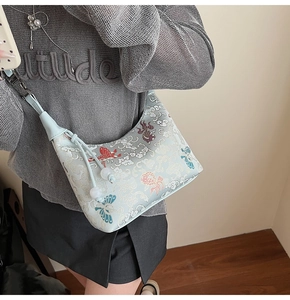 Detail of light blue embroidered canvas bag with butterfly patterns and white pearl tassels