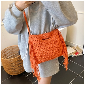 Detail of bright orange hand-woven bag with fringe tassels and braided strap