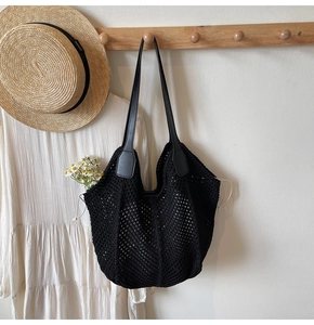 Détail d'un sac cabas en maille crochetée noire avec anses en cuir sur cintre