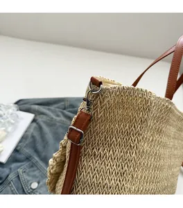 Detail of silver metal buckle and brown leather strap on woven straw beach tote bag