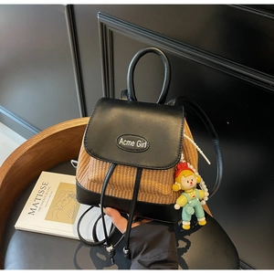 Detail eines Mini-Strohrucksacks mit schwarzem Lederbesatz und süßem Comic-Anhänger