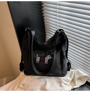 Close-up of black nylon bag featuring sparkling rhinestone dog motif and striped detail