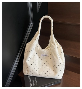 Gros plan d'un sac cabas en toile à pois blancs avec étiquette de marque sur un livre