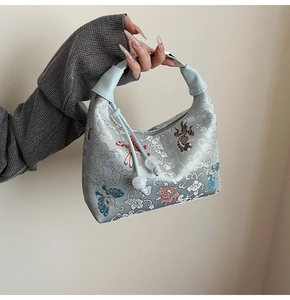 Detailed embroidery of koi fish and floral patterns on a light blue satin hobo bag