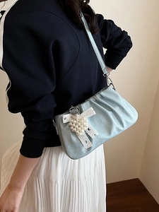 Light blue ruched crossbody bag with heart pearl charm and lace bow on a model