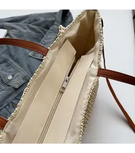 Detail of hollow woven straw tote bag featuring smooth zipper closure and fabric lining