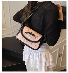 Close-up of pink and black underarm bag with bow prints and a heart pendant