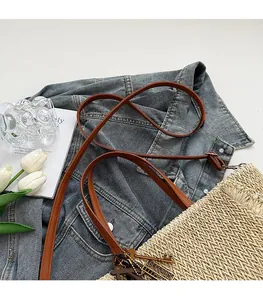 Detailed close-up of woven beige tote bag with leather straps on blue denim