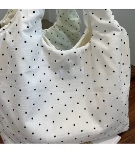 Détail rapproché d'un sac cabas en toile blanche à pois noirs et texture de tissu tissé
