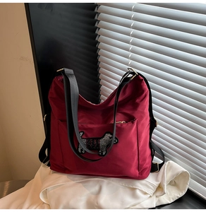 Detail of burgundy nylon backpack featuring a sparkly Scottie dog motif and strap