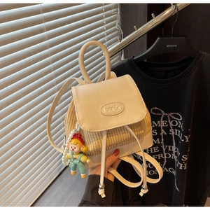 Detail des cremefarbenen Leder-Stroh-Rucksacks mit Acme Girl Logo und Anhänger