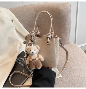 Detail of apricot leather bucket bag with knotted handle and cute teddy bear pendant