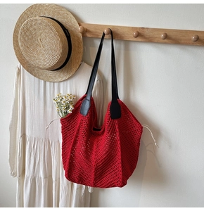 Détail du sac cabas rouge tissé ajouré avec poignée en cuir noir sur cintre en bois