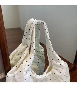 Gros plan d'un sac cabas blanc à pois avec texture gaufre et larges bretelles confortables