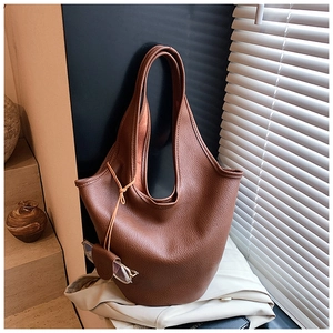 Macro detail of dark brown lychee texture leather bucket bag on light blazer suit