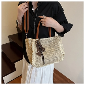 Detail of woven straw tote bag with ruffle trim and leather straps on female model