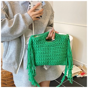 Detail of hand-woven grass green crochet tote bag with long bohemian tassels