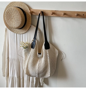 Détail d'un sac en filet tissé avec sangles noires et cordon sur un crochet en bois