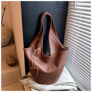 Close-up of deep brown pebbled leather bucket bag with minimalist single handle detail