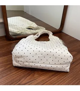 Vue détaillée du sac cabas en toile blanche à pois noirs avec étiquette de marque