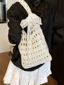 Creamy woven bucket shoulder bag with large lace bow detail for summer vacation style