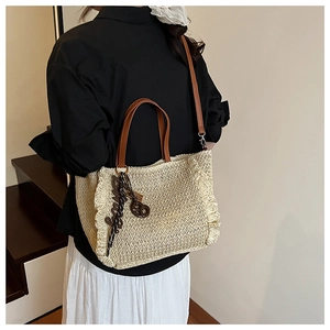 Detail of beige woven straw tote with brown leather handles and ruffled edge details