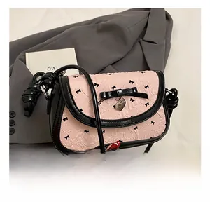 Detailed view of pink bow pattern fabric with heart pendant and contrast black trim