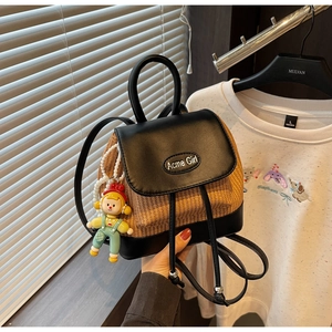 Detailansicht des gewebten Rucksacks mit Acme Girl Metalllogo und süßem Puppenanhänger