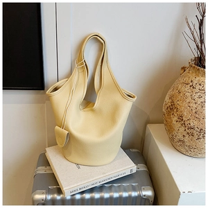 Detail of a creamy yellow lychee texture bucket bag on an elegant luggage setting
