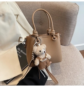 Detail of lychee pattern leather bucket bag with knotted handle and teddy bear charm