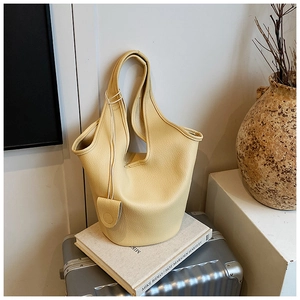 Detail of light yellow lychee grain leather bucket bag with unique circular dual handles