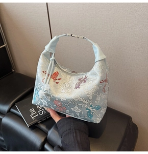 Detailed embroidery on light blue hobo bag with traditional clouds and butterfly motifs