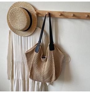Détail du sac cabas en maille tressée avec anses en cuir noir sur crochet en bois