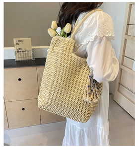 Detail of hand-woven straw tote bag with elegant tassel charm and bead accents