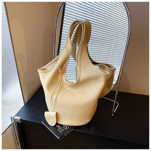 Close-up of cream lychee texture leather bucket bag with heart charm and cross handle
