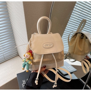 Nahaufnahme des Mini-Rucksacks aus Stroh und Leder mit Logo und süßem Puppen-Anhänger