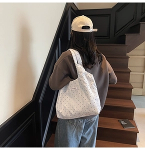 Vue détaillée du sac cabas en toile à pois blancs porté à l'épaule par un mannequin