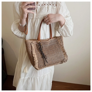 Detailed view of woven beach tote bag with leather handles and ruffled edge accents