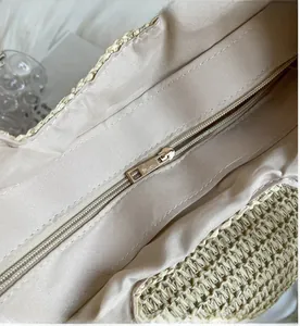 Close-up of smooth gold metal zipper and inner lining of a woven straw tote bag
