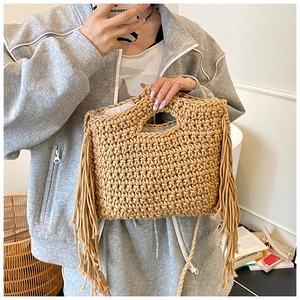 Detail view of handmade straw tote bag with long fringe tassels and hollow handle