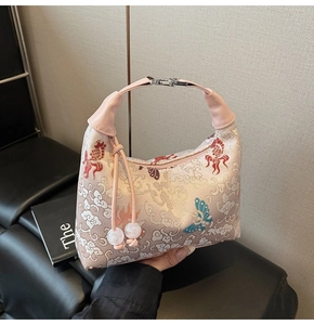 Detail of pink satin handbag featuring traditional embroidery and elegant silk tassels