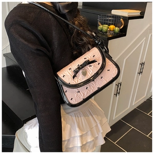 Detail of pink ruffled fabric shoulder bag with black bow and heart-shaped pendant