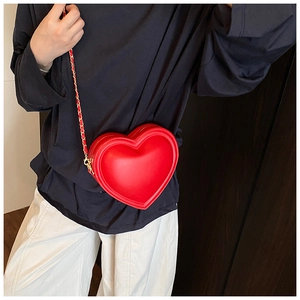 Détail du sac bandoulière rouge en forme de cœur avec chaîne dorée et coutures précises