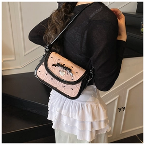 Close-up of pink textured fabric with black bow details and heart charm on small square bag