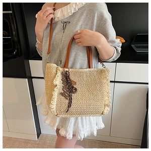 Detail of beige straw tote bag featuring ruffled edges and brown leather handles