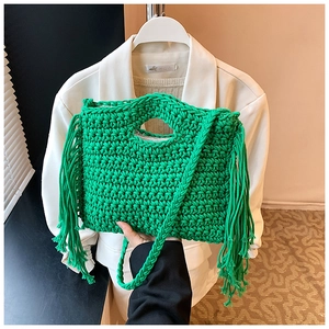 Close-up of green hand-woven knit bag featuring long stylish side fringes and sturdy handle
