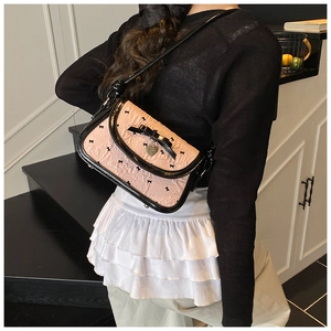 Detail of pink bow shoulder bag with black jacquard patterns and heart pendant