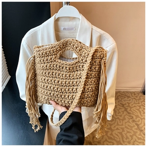Detail of straw woven handbag with side tassels and oval handle in khaki summer style