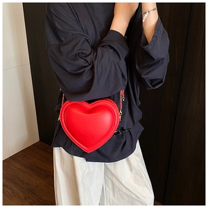 Dettaglio della borsa a tracolla rossa a forma di cuore con catena dorata